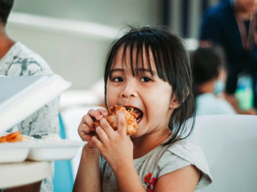 girl biting a good by table at daytime