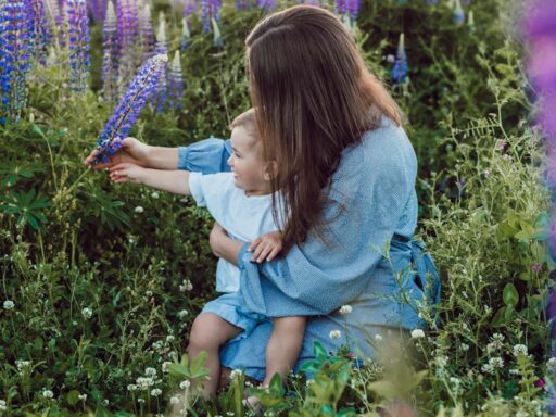 woman sitting with baby on her lap surrounded with purples flower