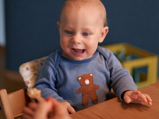 baby in blue sweater sitting on brown wooden high chair