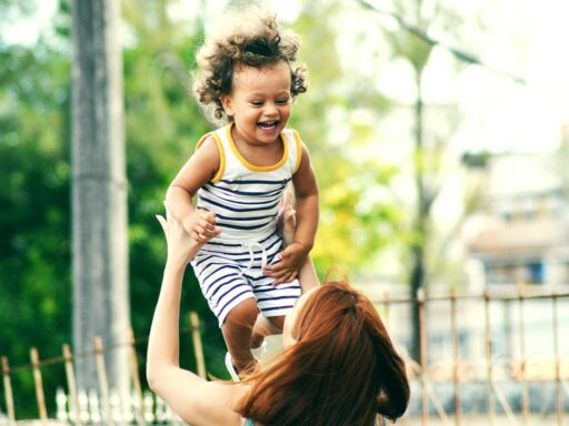 selective focus photo of woman lifting child during daytime