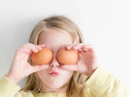 girl holding two eggs while putting it on her eyes