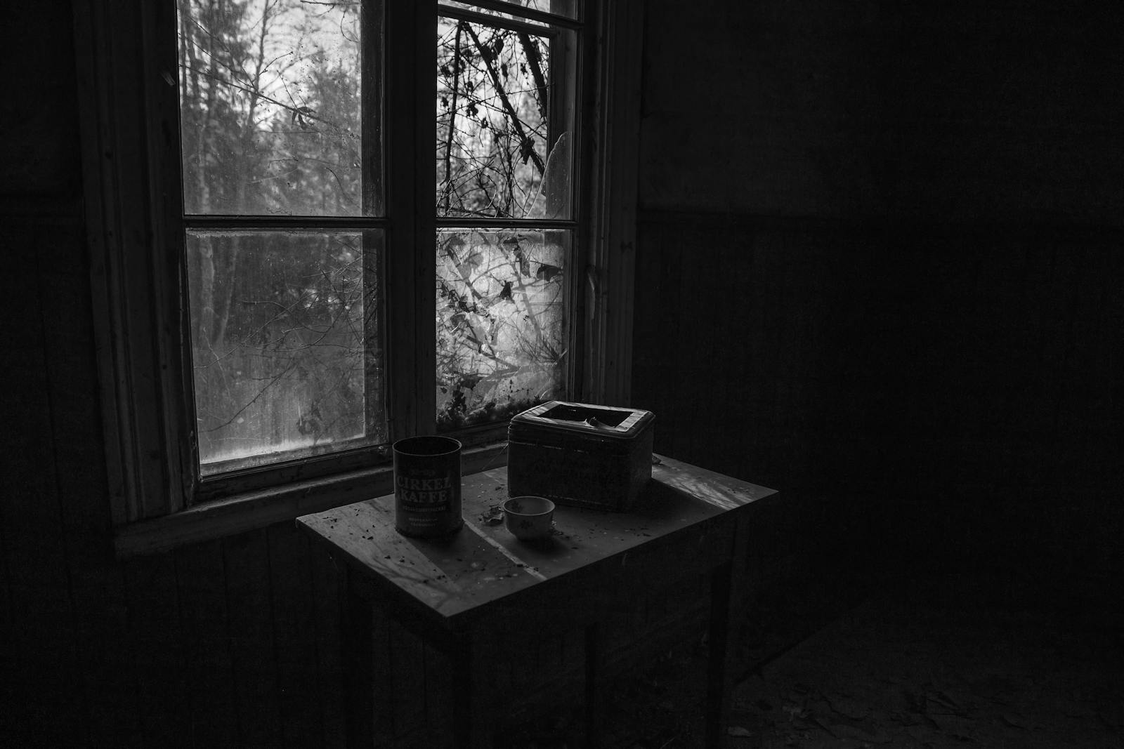 A black and white photo of a table in an abandoned house